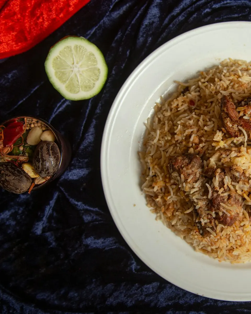 Kacchi gosht biryani heaped on a white plate, with saffron rice and tender mutton
