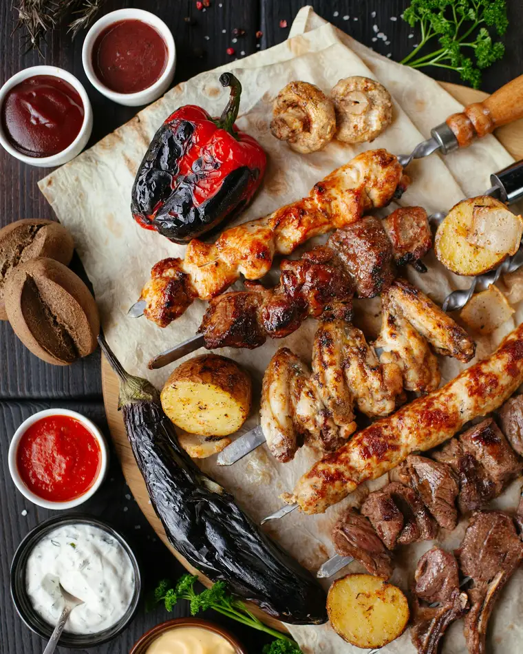 A spread of grilled kebabs, charred peppers and dips